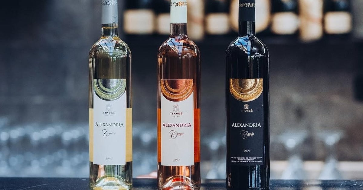 Three Tikveš Alexandria Cuvée bottles, white, rosé and red, standing in a row on a bar.
