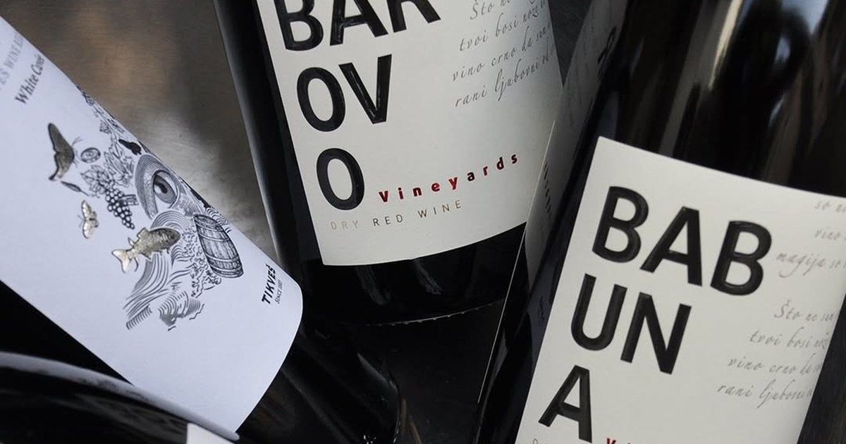 Tikveš Barovo and Babuna red wine bottles lying together on a steel tray, labels facing up.