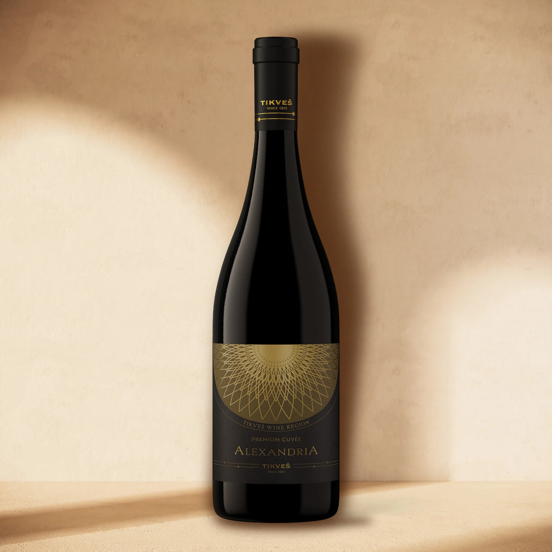 A bottle of Alexandria Premium Cuvée Red standing against a cream wall in soft window light