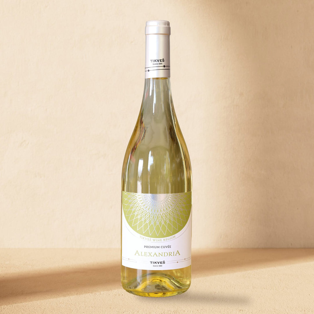 A bottle of Alexandria Premium Cuvée White standing against a cream wall in soft window light