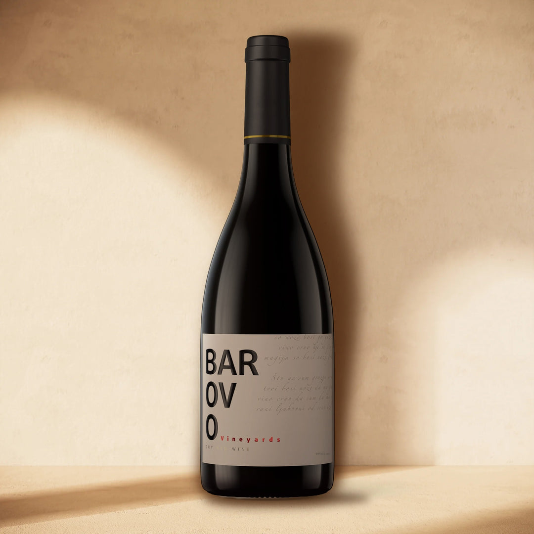 A bottle of Barovo Red standing against a cream wall in soft window light