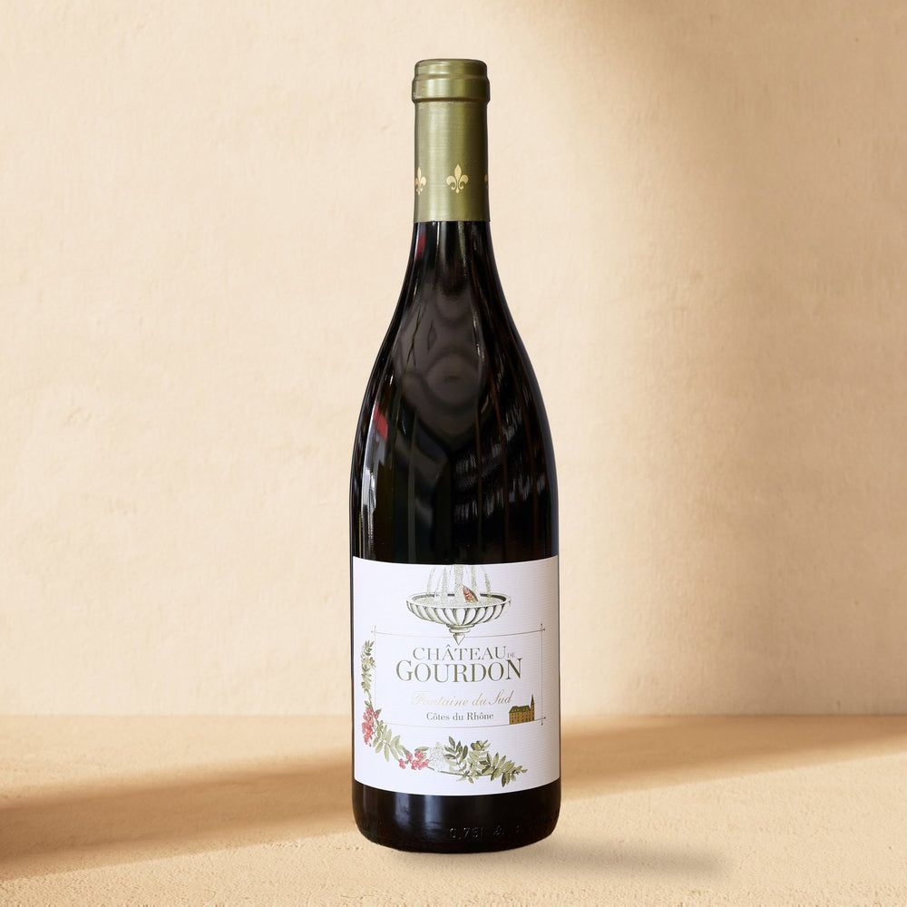 A bottle of Château de Gourdon Fontaine du Sud standing against a cream wall in soft window light