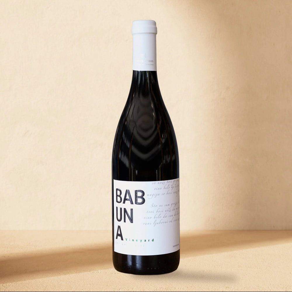 A bottle of Babuna White standing against a cream wall in soft window light