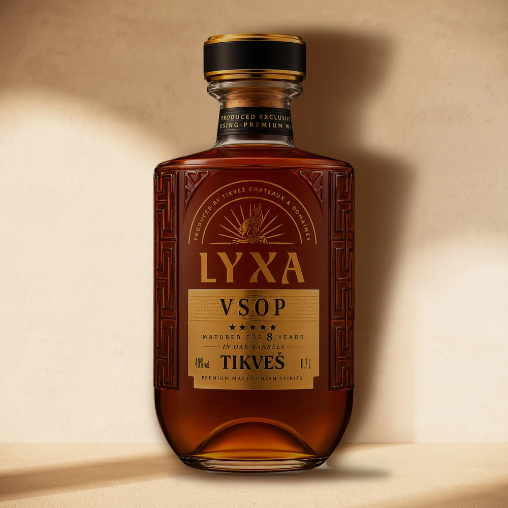 A bottle of LYXA VSOP grape brandy standing against a cream wall in soft window light