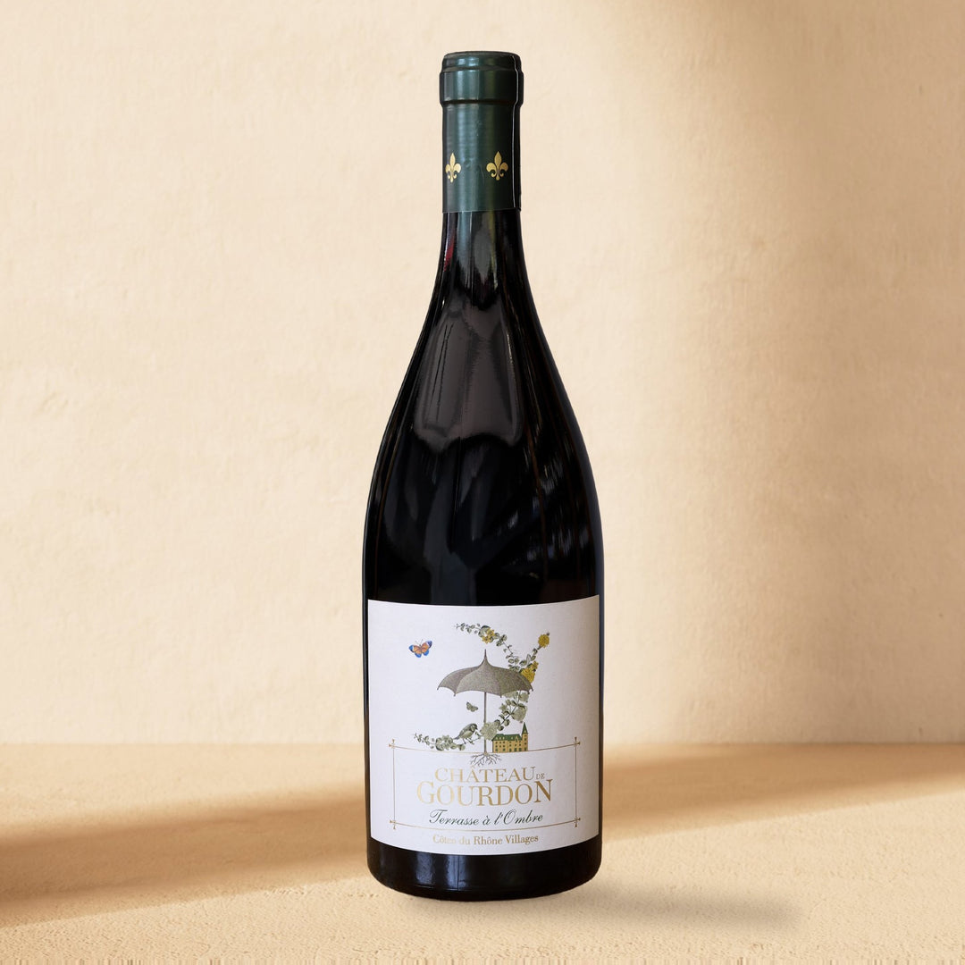 A bottle of Château de Gourdon Terrasse à l'Ombre standing against a cream wall in soft window light