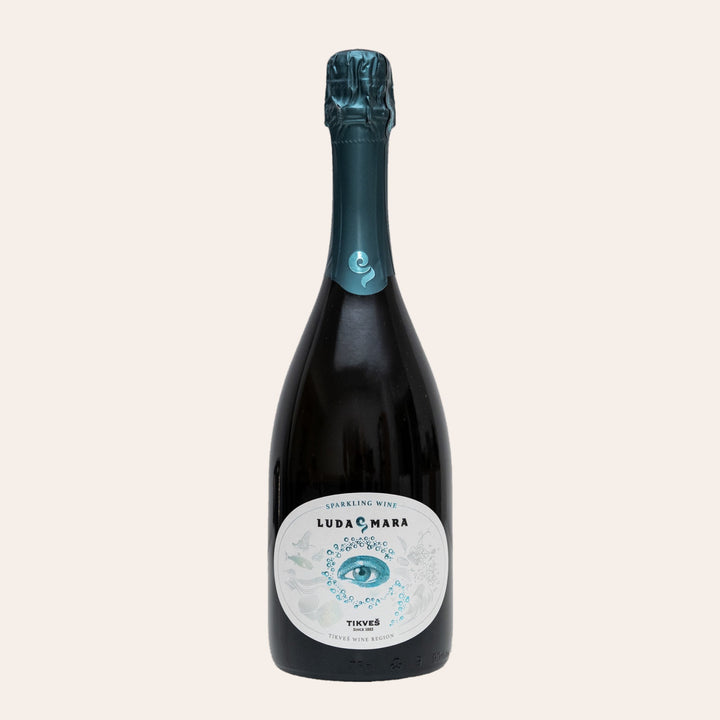 Bottle of Tikveš Luda Mara Sparkling, a dry brut sparkling wine, on a cream background